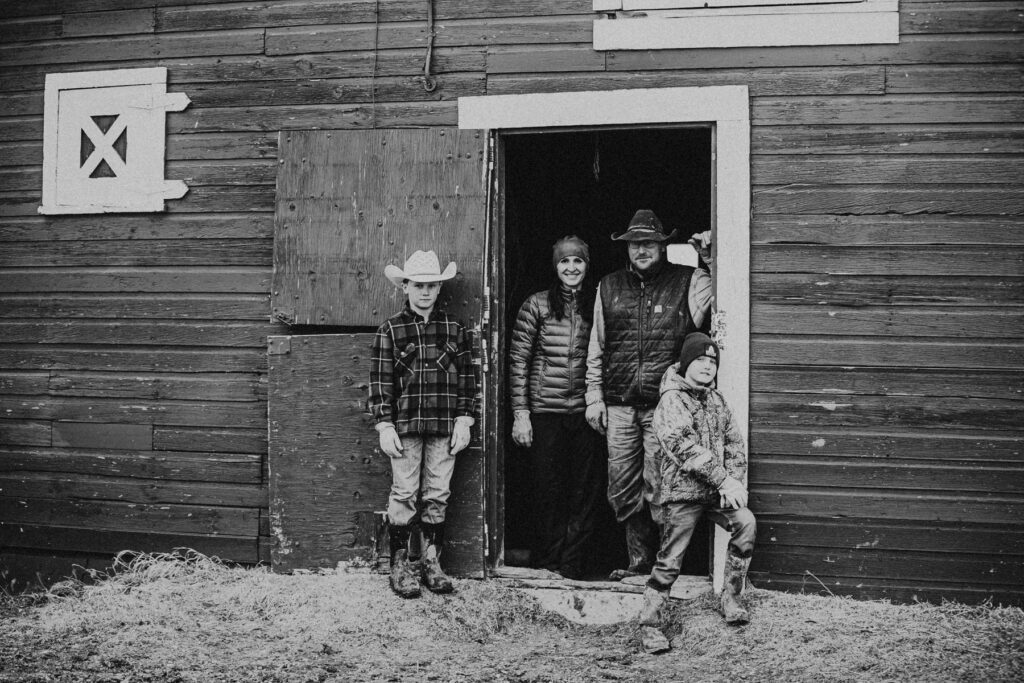 A ranch family standing in the barn door together